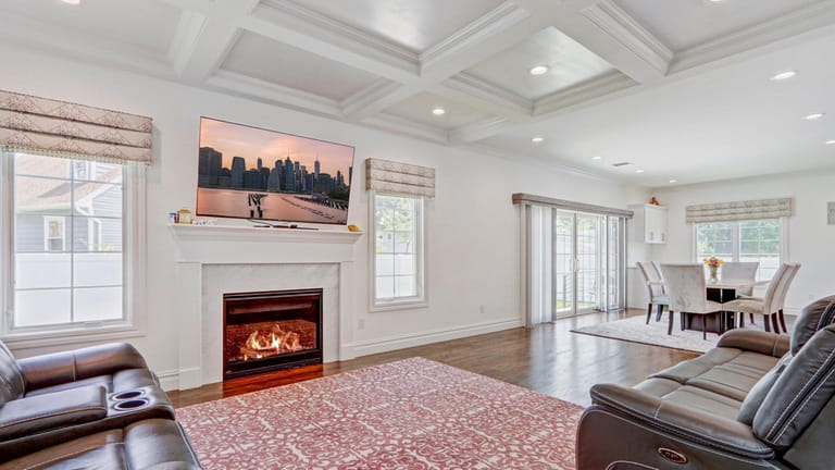 The living room has an electric fireplace and coffered ceiling.