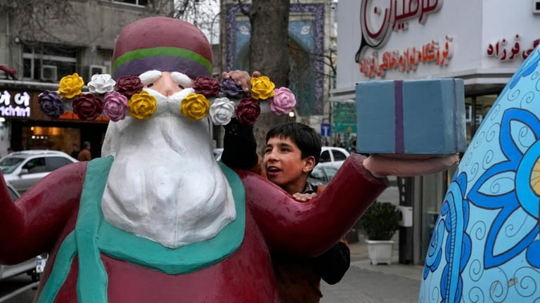 A boy plays with a statue of Amou Nowruz (Uncle...