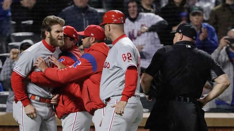 Bryce Harper, left, is restrained by coaches after getting ejected...