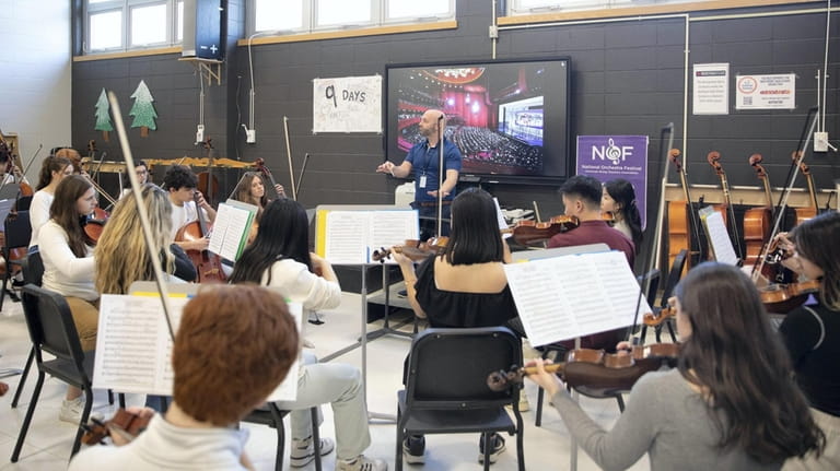 Northport High School orchestra director Michael Susinno conducts the school's...