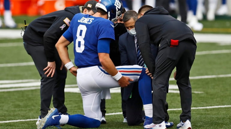 Trainers check Giants quarterback Daniel Jones (8) after an injury...