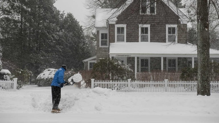 Larry Hillel, of East Hampton, shovels snow in front of...