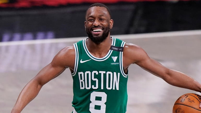 Celtics guard Kemba Walker laughs as he takes the ball...