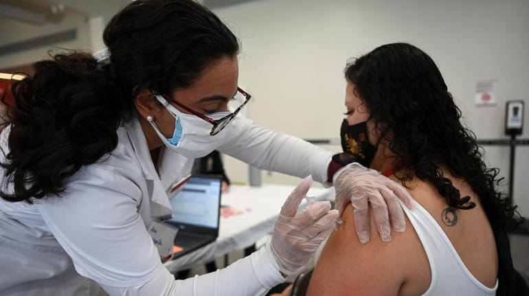 Molloy College nursing student Ana Quintanilla vaccinates Gabriela Procel, of...