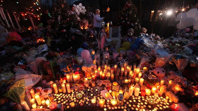 Candles are lit among mementos at a memorial for victims...