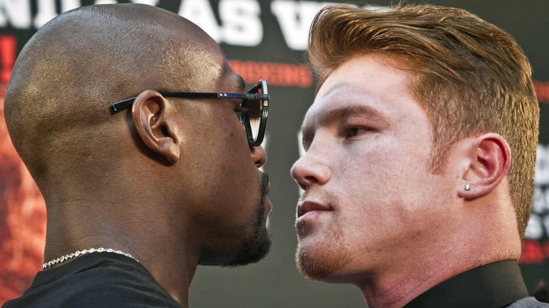 Floyd Mayweather, left, poses in a face-off with Saul "Canelo"...