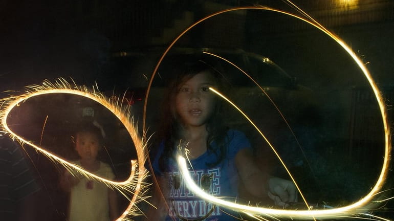 Children twirl sparklers during Fourth of July celebrations on a...