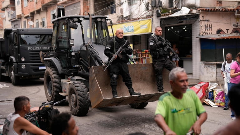 Police ride past residents in a bulldozer they use to...