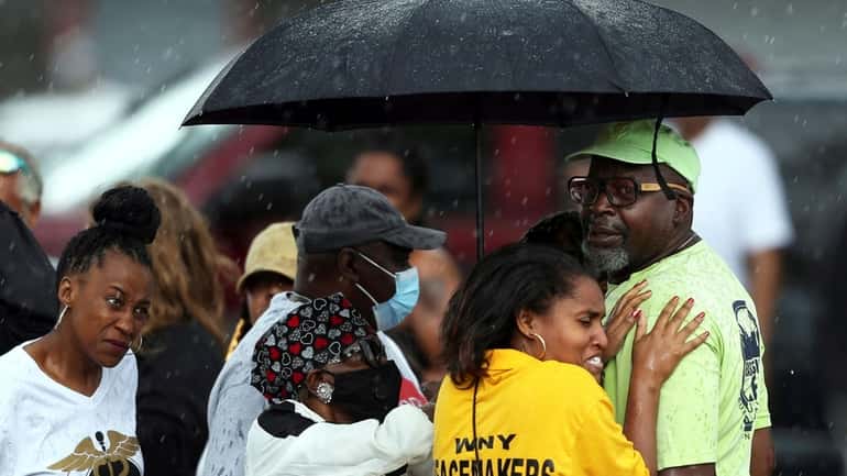 Bystanders gather under an umbrella as rain rolls in after...