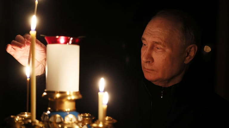 Russian President Vladimir Putin lights a candle to commemorate the...