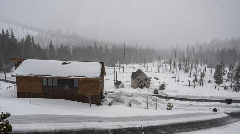 Snow falls on homes on Sierra Pines Road in El...