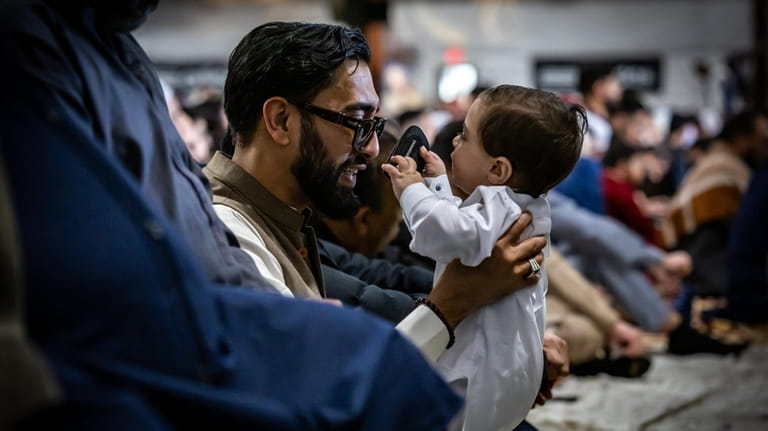A man with a young boy joins other Muslims mark...