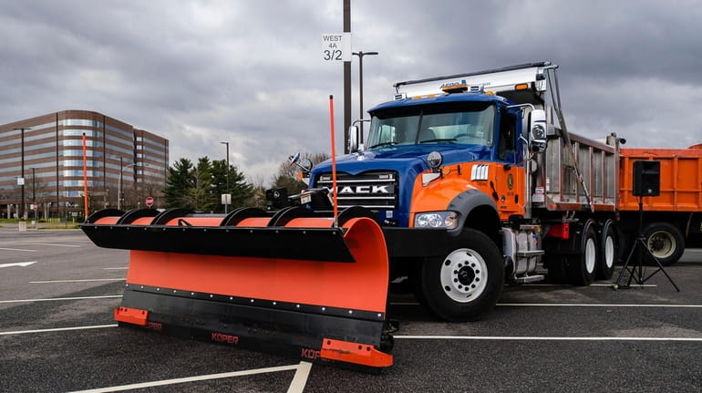 Plows and salt spreaders are on display during a news...