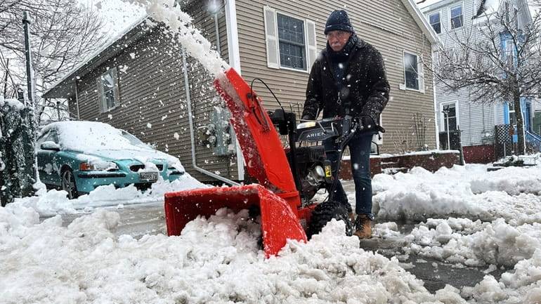 Phil Cloutier removes heavy wet snow after an early-spring Nor'easter,...