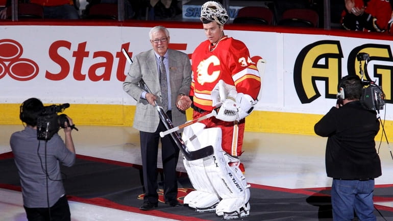 Calgary Flames co-owner Clay Riddell presents a silver stick to...