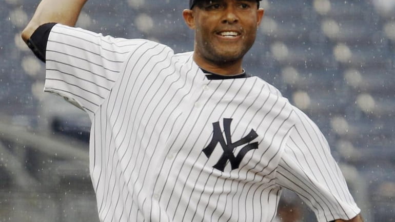 In the rain, Yankees relief pitcher Mariano Rivera throws to...