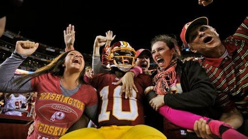 Washington Redskins quarterback Robert Griffin III celebrates with fans after...