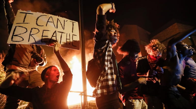 Protestors demonstrate outside of a burning Minneapolis 3rd Police Precinct...