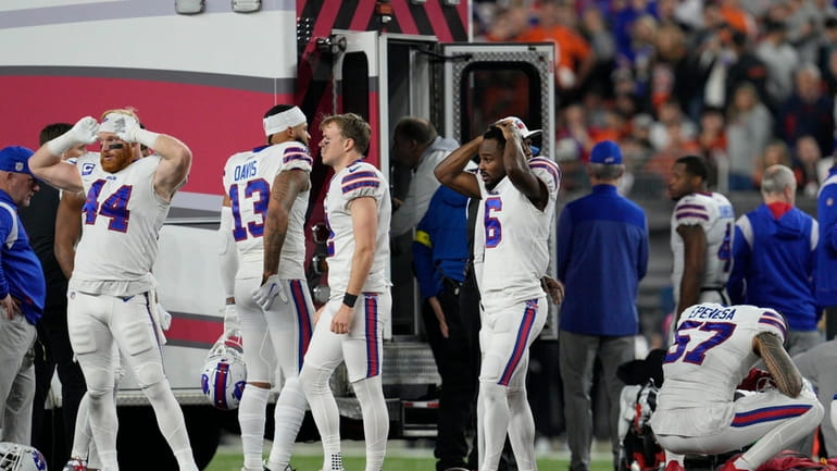Buffalo Bills players react as teammate Damar Hamlin is examined...