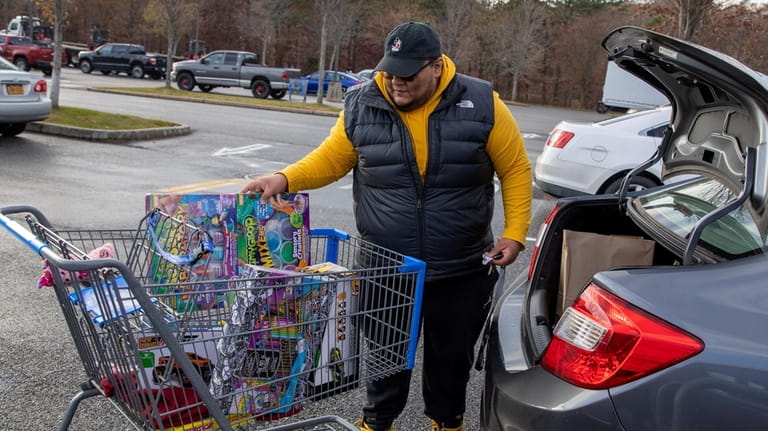 Oscar Cardoza of Brentwood loads his car with the Christmas gifts he...