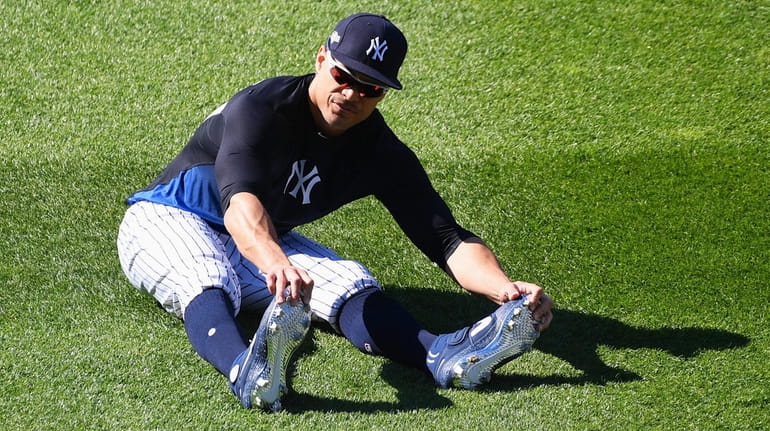 Giancarlo Stanton stretches in the outfield during warmups before Game...