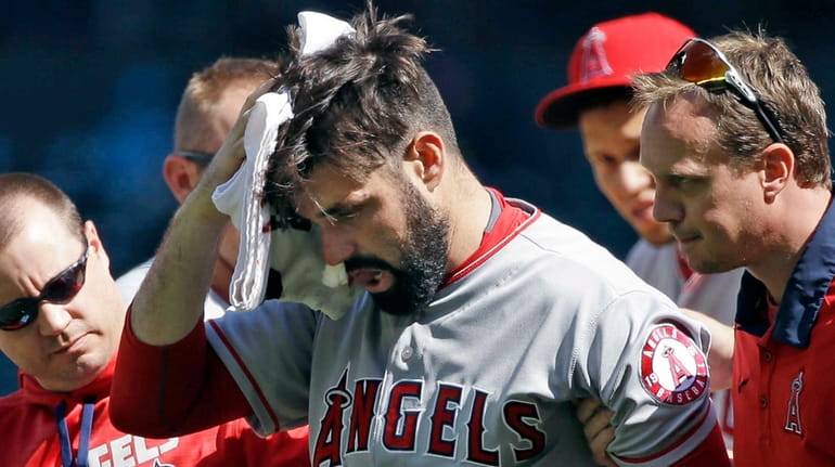 Los Angeles Angels starting pitcher Matt Shoemaker is assisted off...