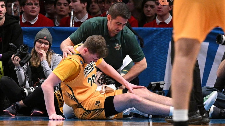 Vermont guard TJ Long is assisted by a trainer after...