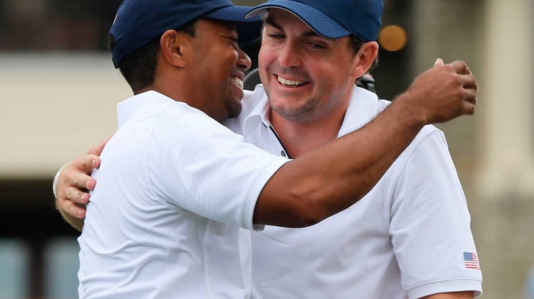 Tiger Woods is hugged by Keegan Bradley on the 18th...