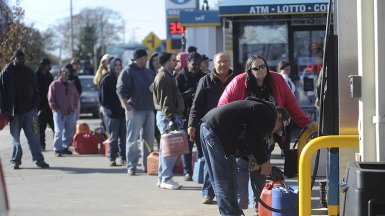 People line up with gas containers to gas up at...