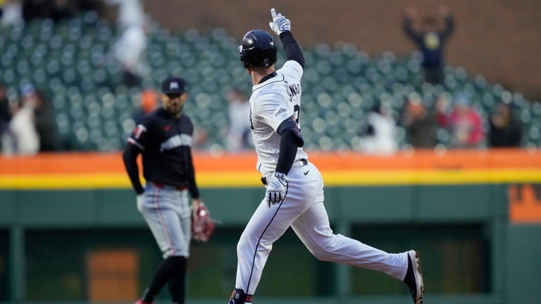 Detroit Tigers' Mark Canha points as he rounds the bases...