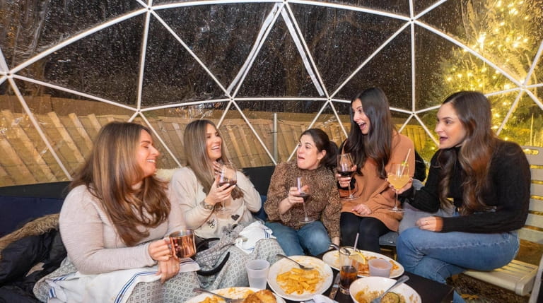 Friends dine in a heated igloo at Coach Meeting House in...