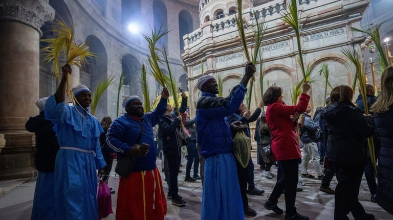 Roman Catholic clergymen carry palm fronds during the Palm Sunday...