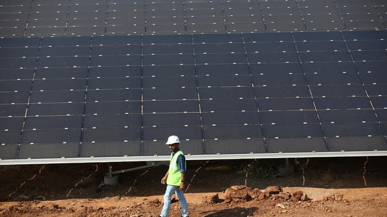 An official walks past solar panels installed at the Pavagada...