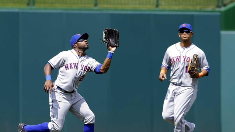 Mets left fielder Eric Young Jr., left, prepares to catch...