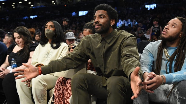 The Nets' Kyrie Irving sits courtside in the third quarter...