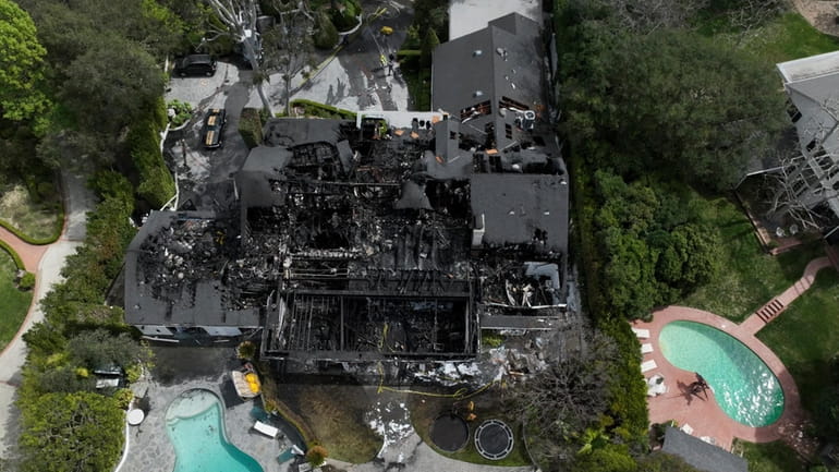 An aerial view shows a fire-damaged property, which appears to...
