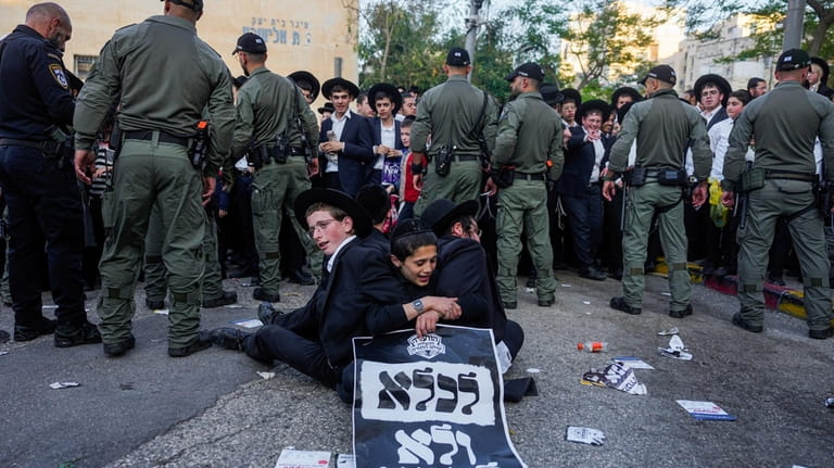 Ultra-Orthodox Jewish men hold a sign in Hebrew that reads...