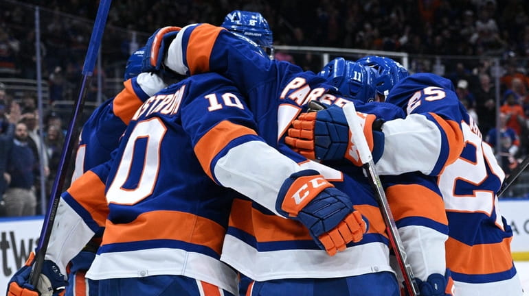 Islanders players celebrate a goal by right wing Simon Holmstrom...