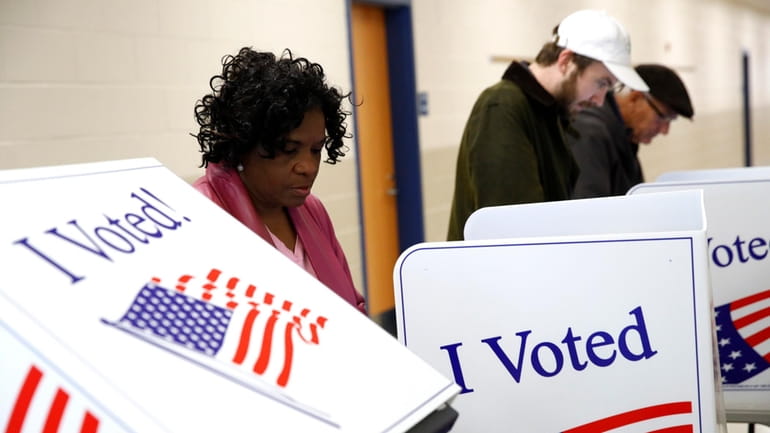 Voters fill out their ballots at a polling place, Feb....