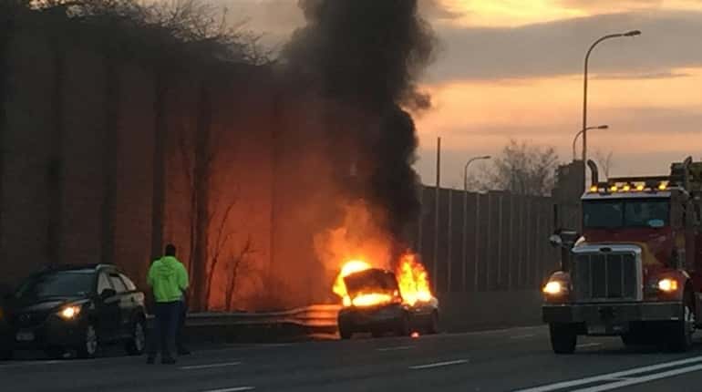 A car fire is seen on the side of the...