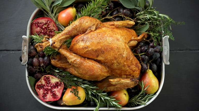 Roast turkey garnished with herbs and autumn fruits.