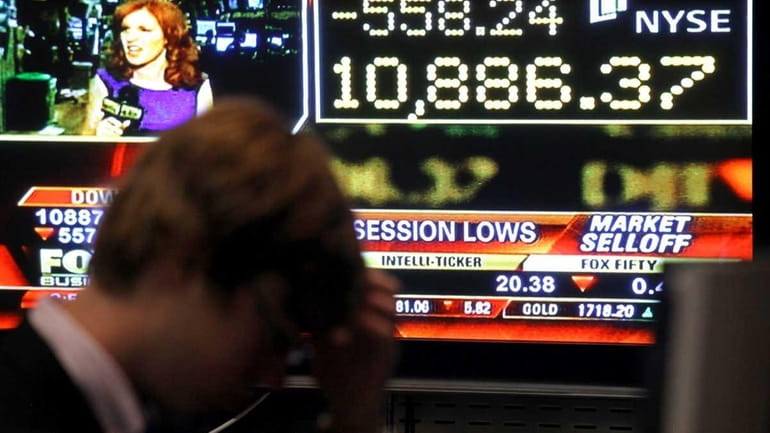 Traders work the floor of the NYSE as the Dow...