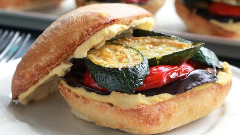 Roasted eggplant, zucchini and bell pepper are sandwiched between hummus...