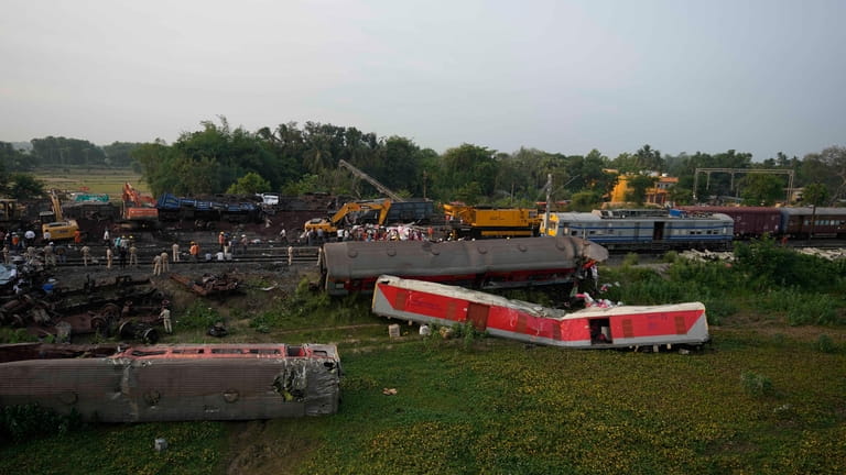 People watch the site where trains that derailed, in Balasore...