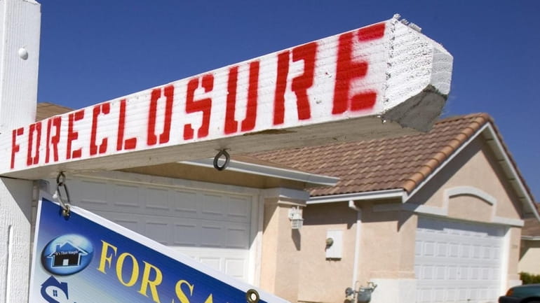 A foreclosure sign is posted outside a house in Stockton,...