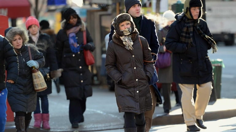 People cross a street in New York, as cold grips...
