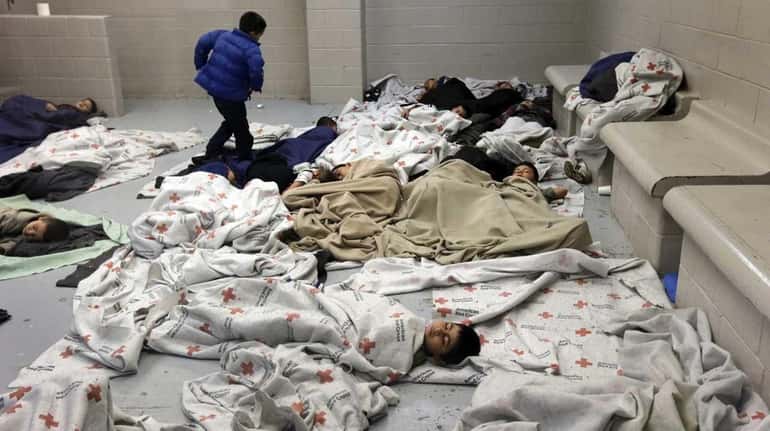 Detainees sleep in a holding cell at a U.S. Customs...