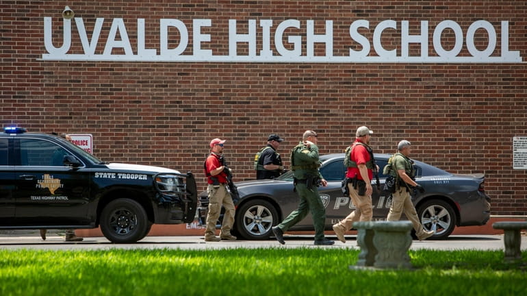 Law enforcement personnel walk outside Uvalde High School after a...