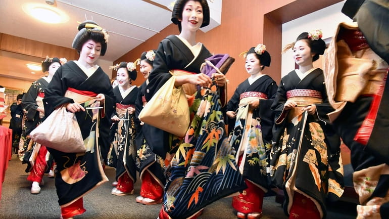 Kimono-clad "geiko" and "maiko" professional entertainers arrive for a ceremony...