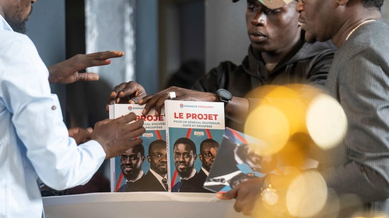 Members of Bassirou Diomaye Faye's campaign display a book called...
